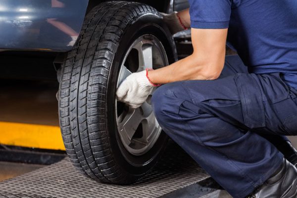 Low section of mechanic fixing car tire at auto repair shop